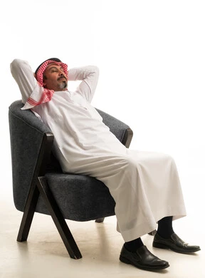 رجل سعودي بالثوب التقليدي يسترخي على كرسي