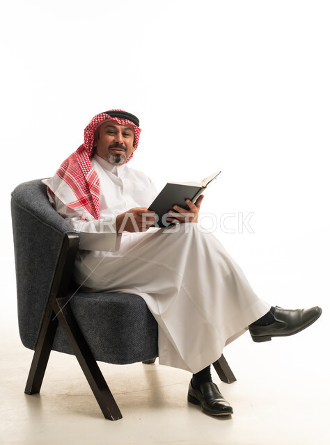 رجل سعودي بالزي التقليدي يقرأ كتاباً في الاستوديو