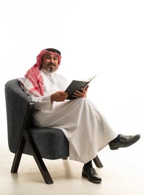 رجل سعودي بالزي التقليدي يقرأ كتاباً في الاستوديو