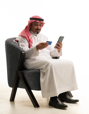 رجل سعودي يستخدم بطاقة ائتمان وهاتف ذكي على خلفية بيضاء