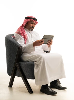 رجل سعودي بالزي التقليدي يستخدم جهاز لوحي في الاستوديو