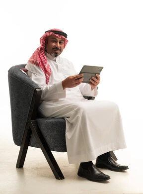 رجل سعودي بالزي التقليدي يحمل جهاز لوحي
