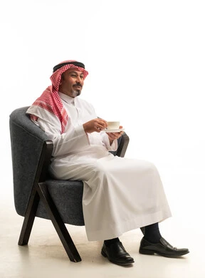 رجل سعودي بالزي التقليدي يجلس مع فنجان قهوة