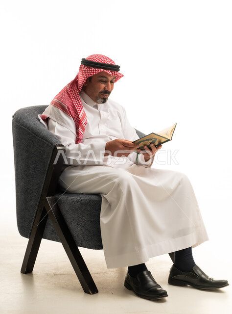 رجل سعودي بالزي التقليدي يقرأ كتاباً