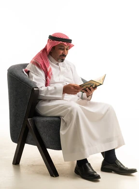 رجل سعودي بالزي التقليدي يقرأ كتاباً