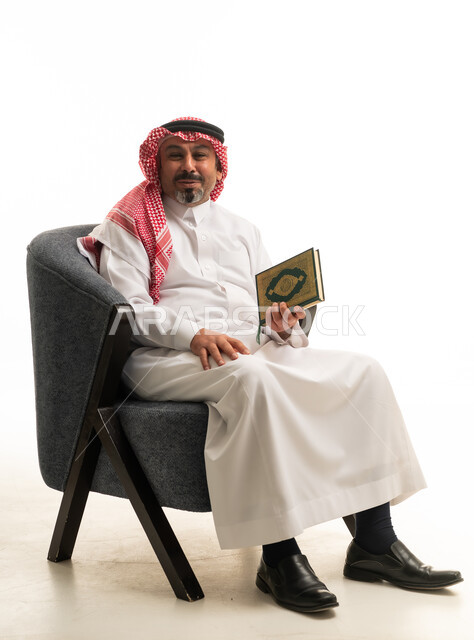رجل سعودي يرتدي الثوب ويمسك المصحف الشريف