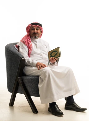 رجل سعودي يرتدي الثوب ويمسك المصحف الشريف