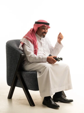 رجل سعودي باللباس التقليدي يلعب ألعاب الفيديو