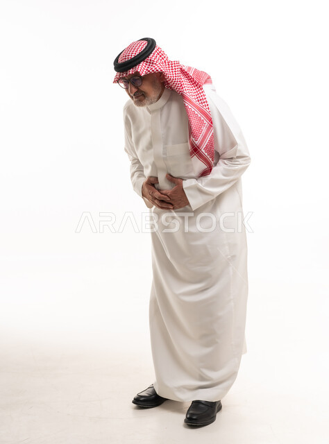 رجل سعودي مسن يعاني من ألم في البطن بخلفية بيضاء