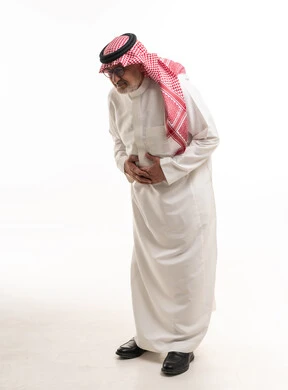 رجل سعودي مسن يعاني من ألم في البطن بخلفية بيضاء
