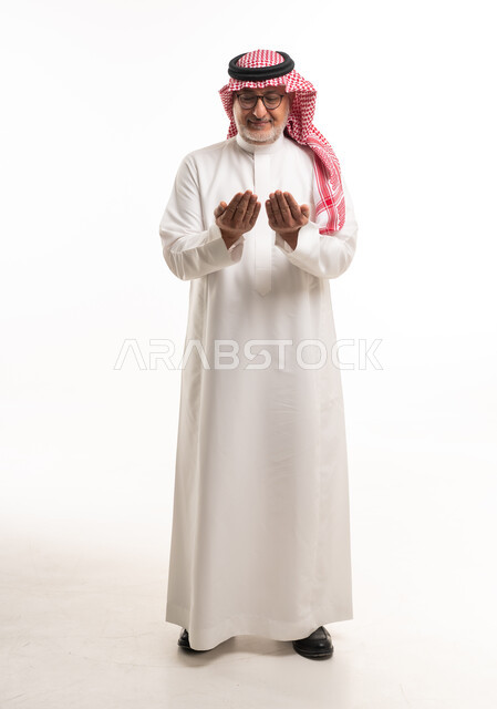 رجل سعودي مسن يدعو بالزي الشعبي التقليدي
