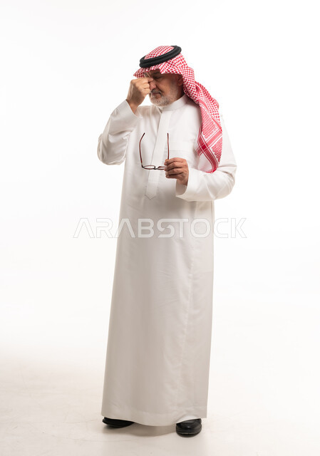 رجل سعودي مسن يعاني من الصداع بالزي التقليدي