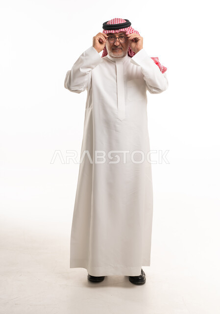 رجل سعودي مسن يرتدي الثوب والنظارات في استوديو