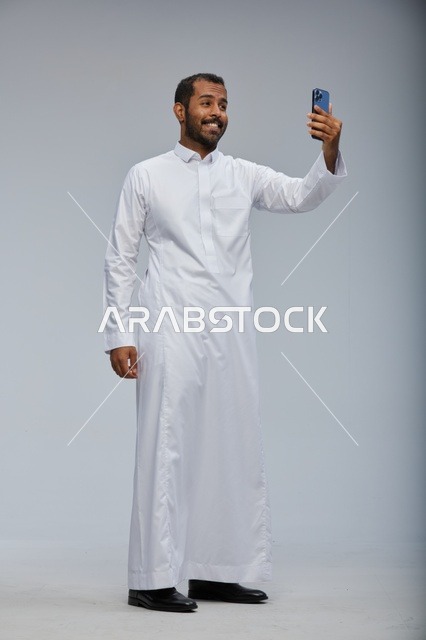 رجل سعودي بالثوب الأبيض يلتقط سيلفي في الاستوديو