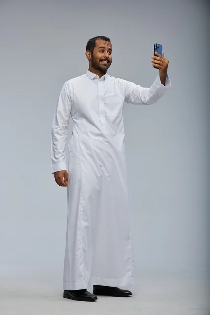 Saudi Man in White Thobe Taking a Selfie in a Studio