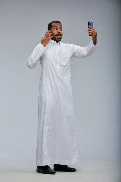رجل سعودي بالثوب الأبيض يلتقط سيلفي بالهاتف الذكي