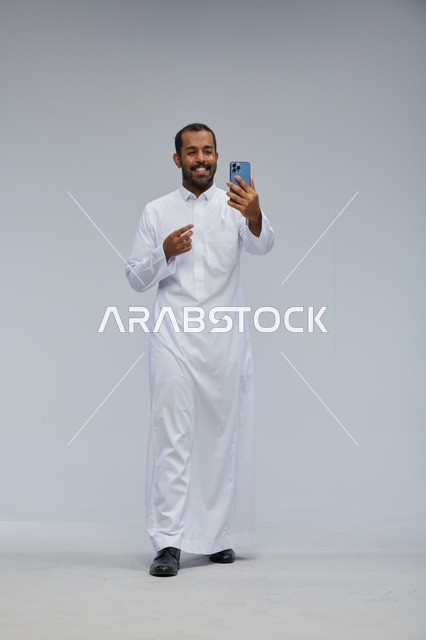 رجل سعودي بالثوب الأبيض يلتقط سيلفي بالهاتف