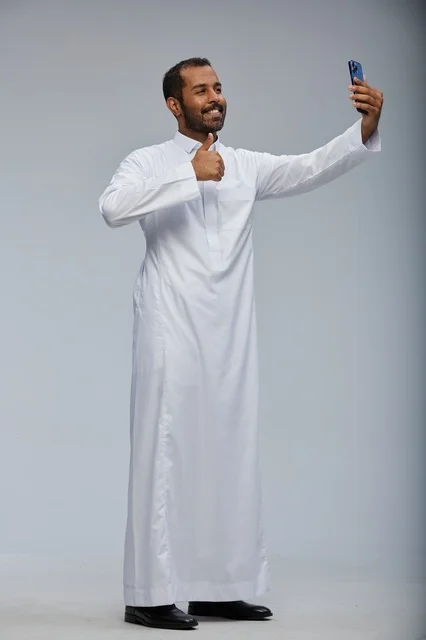 Saudi Man in White Thobe Taking Selfie with Smartphone