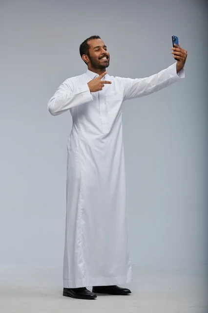 Saudi Man in White Thobe Taking Selfie with Smartphone