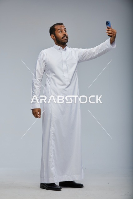 رجل سعودي بالثوب الأبيض يلتقط سيلفي بالجوال