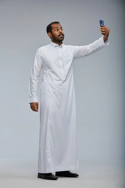 رجل سعودي بالثوب الأبيض يلتقط سيلفي بالجوال