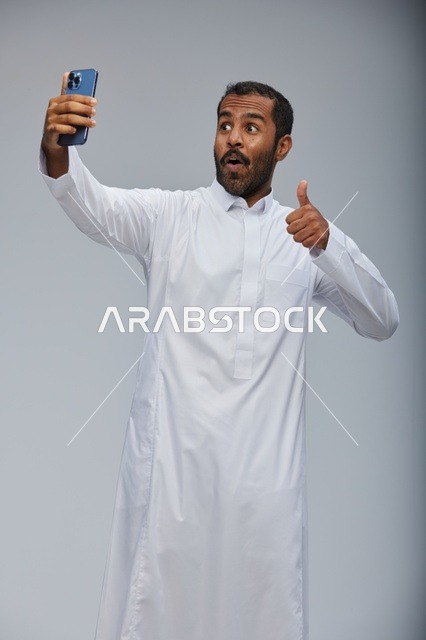 رجل سعودي بالثوب الأبيض يلتقط سيلفي بالهاتف