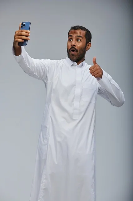 رجل سعودي بالثوب الأبيض يلتقط سيلفي بالهاتف