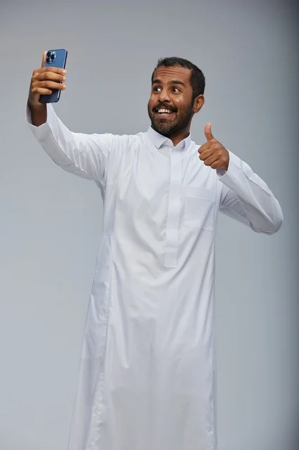 Saudi Man in Traditional Thobe Taking Selfie with Smartphone