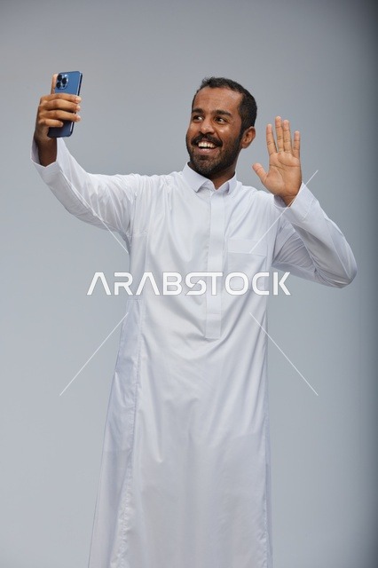 رجل سعودي بالثوب التقليدي يلتقط صورة سيلفي بالجوال