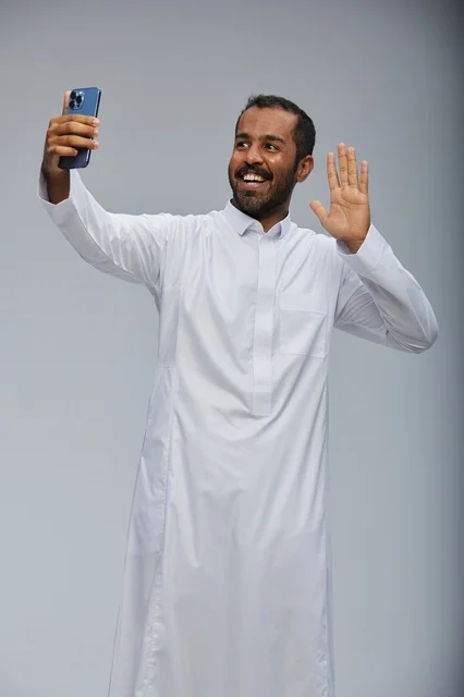 رجل سعودي بالثوب التقليدي يلتقط صورة سيلفي بالجوال