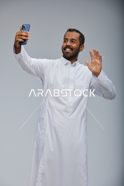 رجل سعودي بالثوب الأبيض يلتقط صورة سيلفي بالهاتف