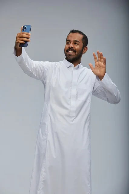 رجل سعودي بالثوب الأبيض يلتقط صورة سيلفي بالهاتف رجل سعودي بالثوب الأبيض يلتقط صورة سيلفي بالهاتف