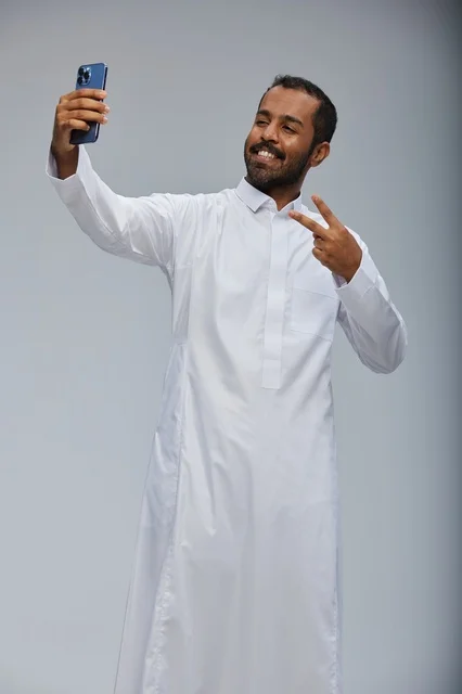 Saudi Man in White Thobe Taking Selfie with Smartphone