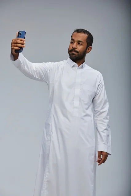 رجل سعودي بالثوب الأبيض يلتقط سيلفي بالجوال