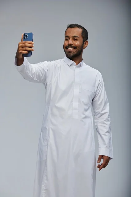 Saudi Man in White Thobe Taking Selfie with Smartphone