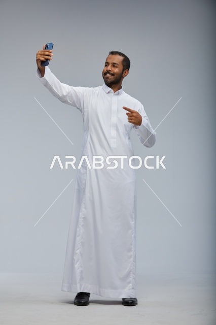 رجل سعودي بالثوب الأبيض يلتقط سيلفي في الاستوديو