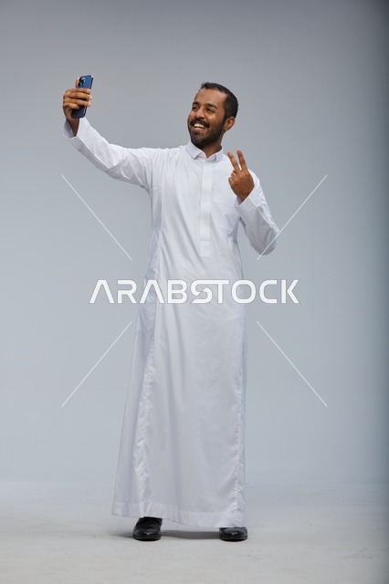 رجل سعودي بالثوب الأبيض يلتقط صورة سيلفي