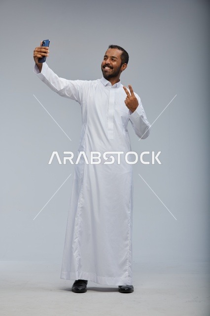 رجل سعودي بالثوب الأبيض يلتقط سيلفي بالهاتف