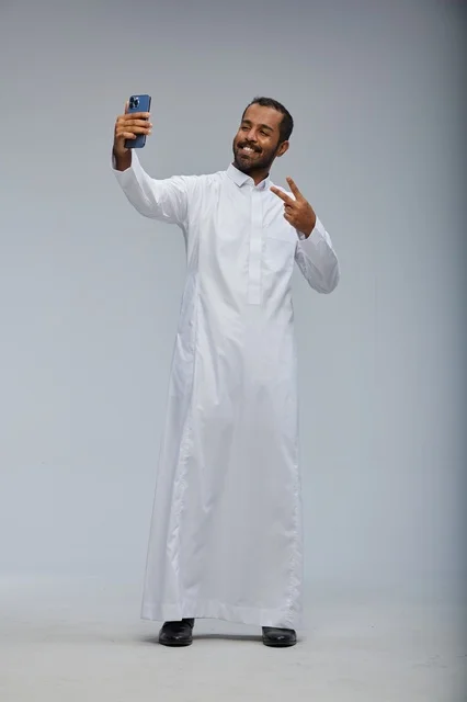 Saudi Man in White Thobe Taking Selfie with Smartphone