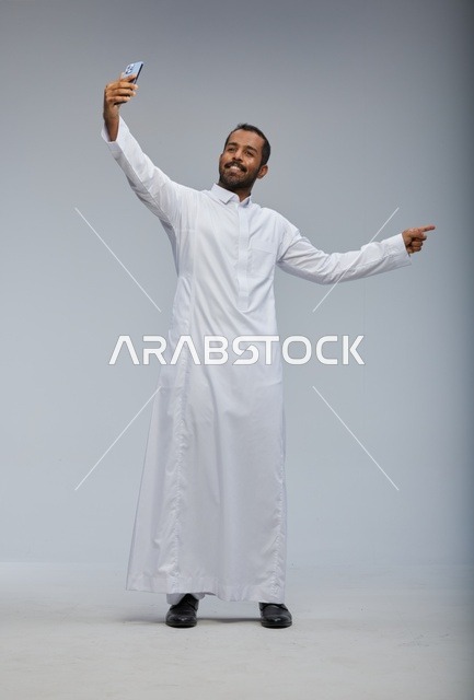 رجل سعودي بالثوب الأبيض يلتقط سيلفي بالجوال