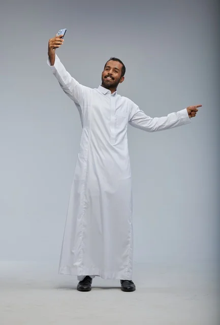 رجل سعودي بالثوب الأبيض يلتقط سيلفي بالجوال