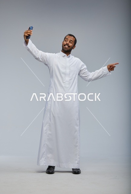 رجل سعودي بالثوب الأبيض يلتقط سيلفي ويشير للجانب