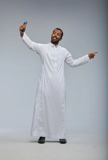 رجل سعودي بالثوب الأبيض يلتقط سيلفي ويشير للجانب