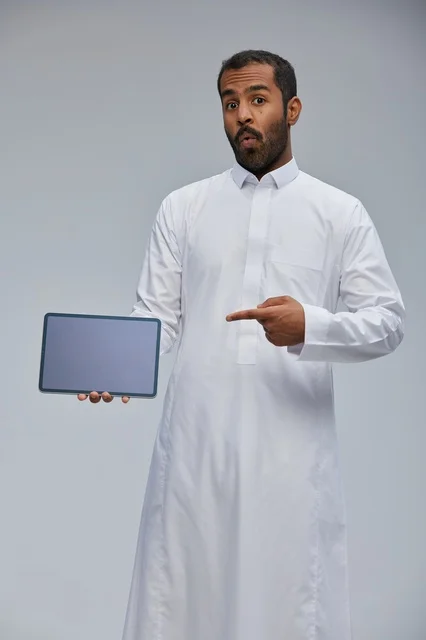 Saudi Man in Thobe Pointing at Tablet Screen Studio Shot