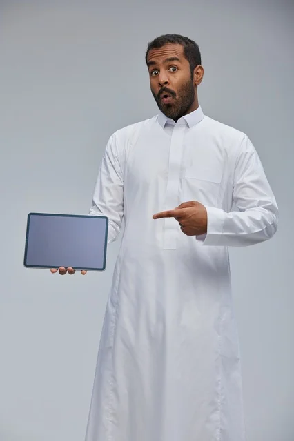 Saudi Man in White Thobe Holding Digital Tablet