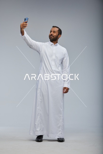 رجل سعودي بالثوب الأبيض يلتقط سيلفي في الاستوديو