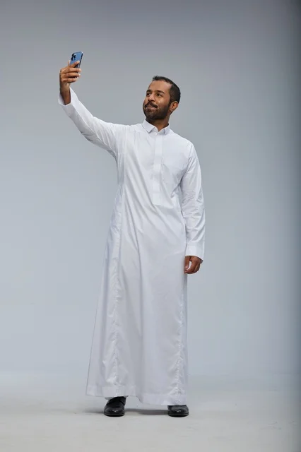 رجل سعودي بالثوب الأبيض يلتقط سيلفي في الاستوديو