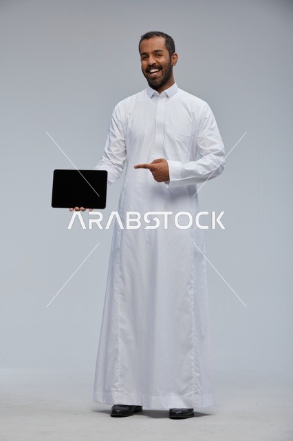 رجل سعودي بالثوب الأبيض يشير إلى جهاز لوحي