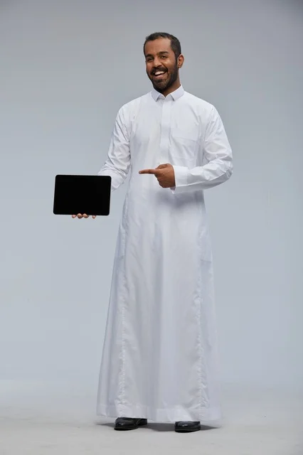 Saudi Man in White Thobe Pointing at Digital Tablet