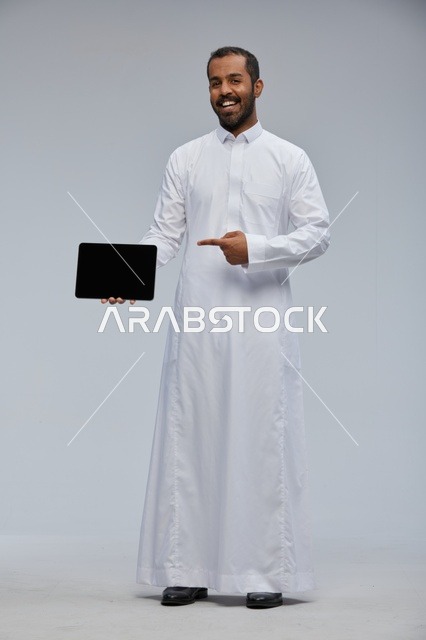 رجل سعودي بالثوب الأبيض يحمل جهاز لوحي ذكي استوديو